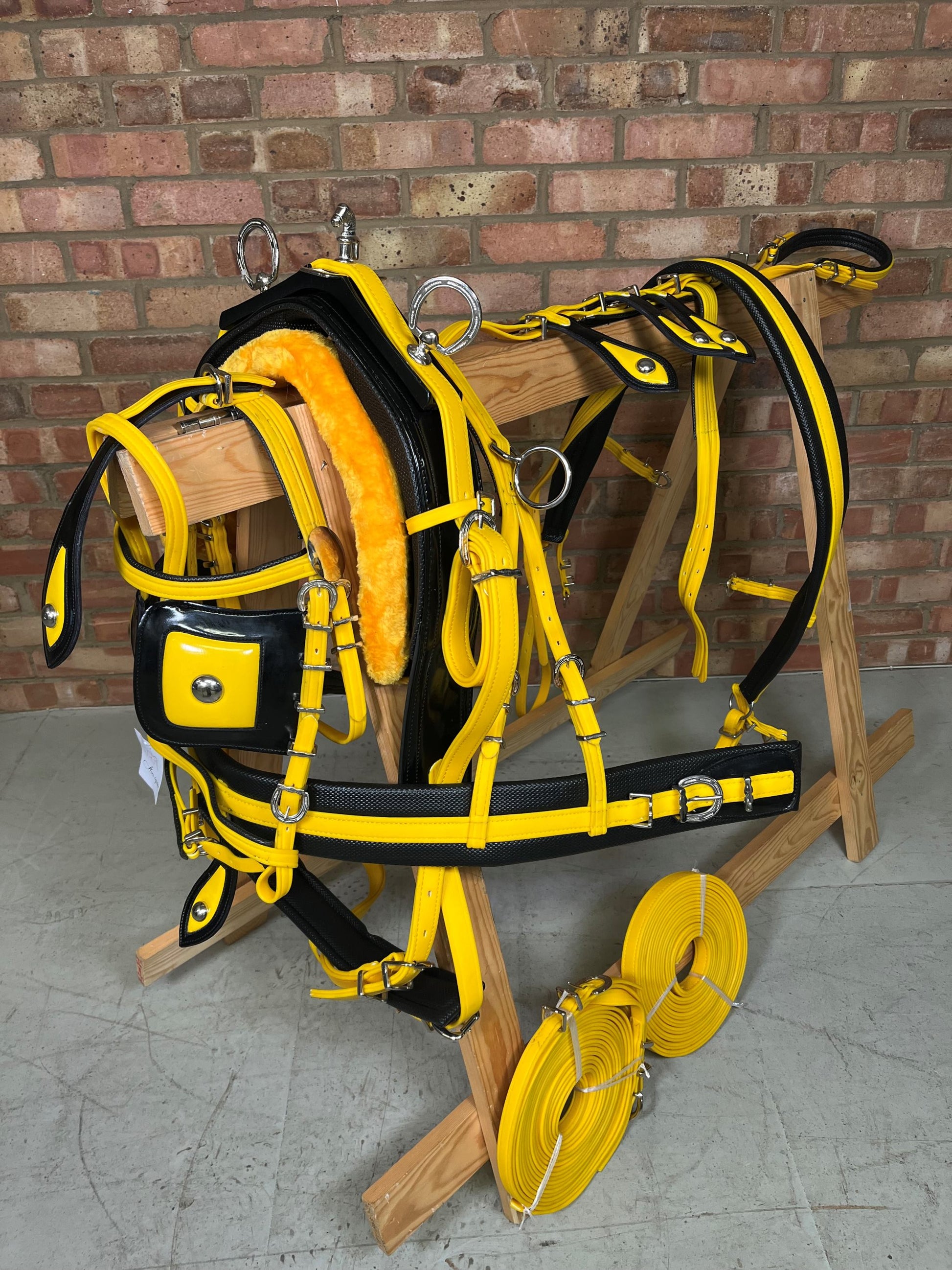 A yellow and black breeching harness with soft bio-thane padding, horse shoe buckle, and square winkers